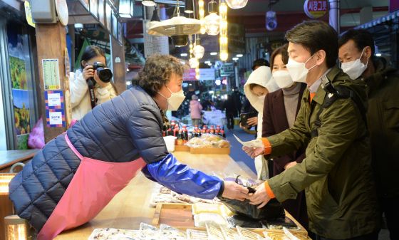 ▲안철수 국민의당 대선 후보가 지난해 12월 5일 오후 충북 청주시 육거리 종합시장을 찾아 떡을 구매하고 있다. /사진=뉴시스