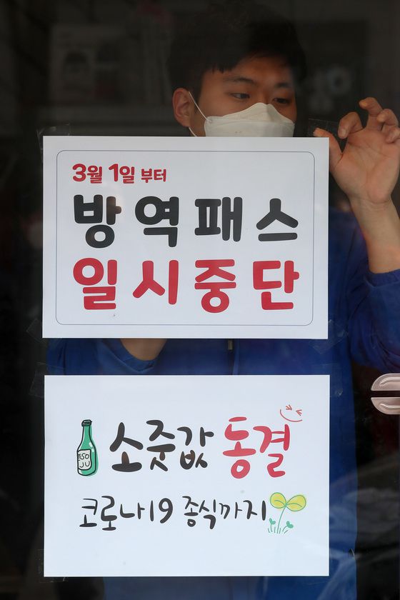 (대구=뉴스1) 공정식 기자 = 28일 오후 대구 중구의 한 음식점 유리문에 식당 직원이 3월 1일부터 시행되는 방역패스 일시중단 관련 안내문을 붙이고 있다.    방역패스 일시중단 안내문 아래 소줏값 동결 안내문이 붙어 있다. 음식점 주인은 "소주 출고가는 인상됐지만 코로나19 확산 속에 가게를 찾아준 손님을 생각해 코로나 종식 때까지 소줏값을 인상하지 않겠다"고 말했다. 2022.2.28/뉴스1