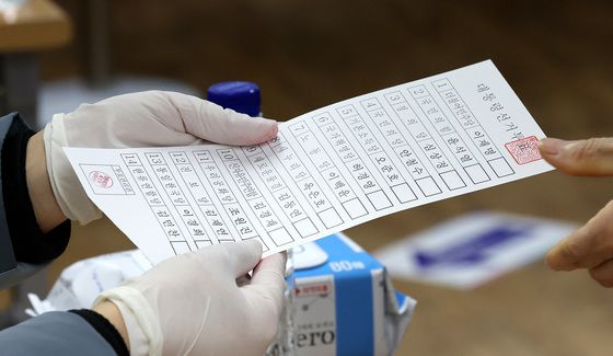제20대 대통령선거 투표일인 9일 오전 서울 성북구 성북아동청소년센터에 마련된 투표소를 찾은 시민이 투표용지를 받고 있다./사진=뉴스1
