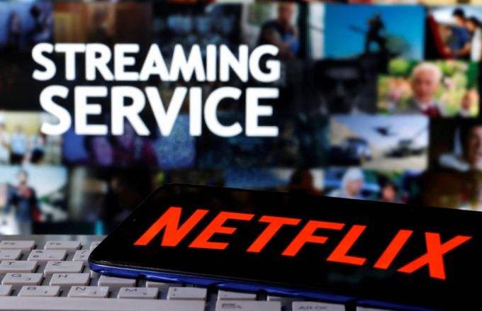 A smartphone with the Netflix logo is seen on a keyboard in front of displayed "Streaming service" words in this illustration taken March 24, 2020. REUTERS/Dado Ruvic/File Photo