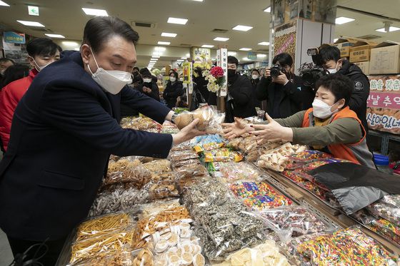 (군산=뉴스1) 구윤성 기자 = 윤석열 국민의힘 대선 후보가 22일 오후  전북 군산시 군산공설시장의 한 전통 과자 가게를 찾아 전병을 골라 상인에게 건네주고 있다. 2022.2.22/뉴스1