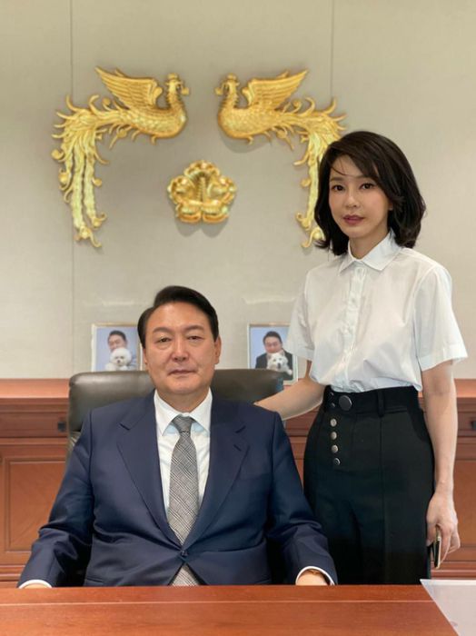 윤석열 대통령과 부인 김건희 여사가 용산 대통령실 집무실에서 나란히 기념촬영하는 모습이 공개됐다. 배경으로 대통령을 상징하는 봉황 휘장과 반려견 토리, 써니의 사진이 보인다. (대통령실 관계자 제공) /사진=뉴스1