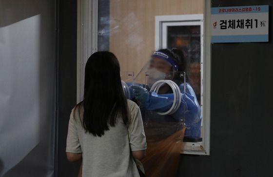 (서울=뉴스1) 박세연 기자 = 27일 저녁 서울 중구 서울역 신종 코로나바이러스(코로나19) 임시선별검사소에서 한 시민이 PCR검사를 받고 있다.   이날 코로나19 신규 확진자는 10만285명 발생해 3개월만에 10만명을 넘었다. 2022.7.27/뉴스1