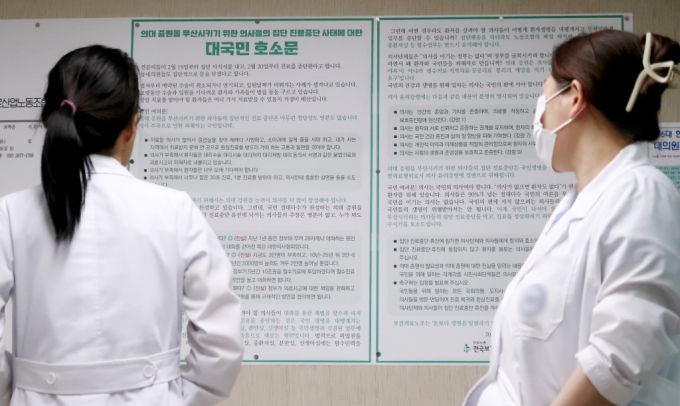정부의 의대정원 확대 정책에 반발하는 전공의 단체행동이 8일째 이어진 지난달 27일 오후 서울의 한 대학병원에서 의사들이 '의대 증원을 무산시키기 위한 의사들의 집단 진료중단 사태에 대한 대국민 호소문'을 바라보고 있다./사진=뉴스1