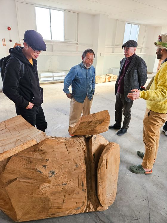 목조각가 신조요시히로씨가 조관제 한국만화영상진흥원이사장과 한국작가들에게 작품에 대한 설명을 하고 있다./사진제공=한국카툰협회