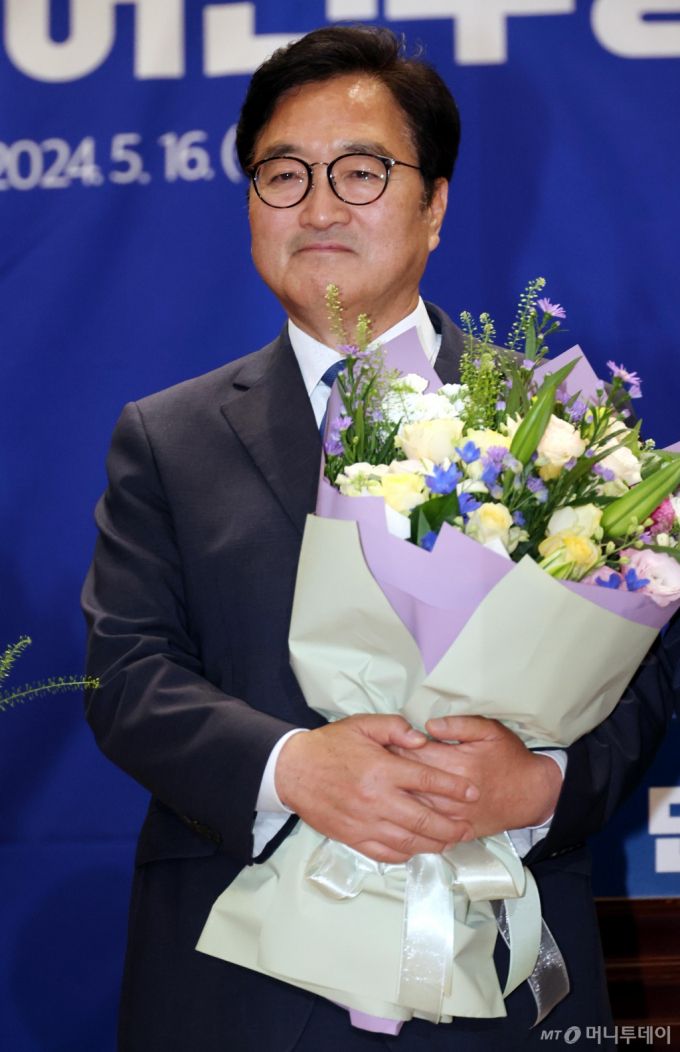 [서울=뉴시스] 조성우 기자 = 22대 국회 전반기 국회의장 후보로 선출된 우원식 더불어민주당 의원이 16일 오전 서울 여의도 국회 의원회관에서 열린 제22대 국회 전반기 국회의장단 후보 선출 당선자 총회에서 이재명 대표에게 받은 꽃다발을 들고 있다.  2024.05.16. xconfind@newsis.com /사진=조성우