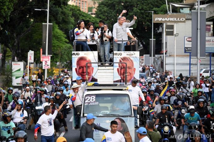 베네수엘라 야권 후보인 에드문도 곤살레스 우루티아와 야당지도자 마리아 코리나 마차도가 차량에 올라 25일 카라카스에서 막바지 대선 유세를 벌이고 있다. 오는 일요일인 28일 치러지는 베네수엘라 대선에서는 3선 도전에 나선 니콜라스 마두로 현 대통령과 이를 저지하려는 우루티아 후보간 '박빙의 대결'이 예상된다. 앞서 마두로 대통령은 자신의 패배시 '베네수엘라가 내전으로 피바다가 될 것'이라며 대선 결과 불복 가능성을 내비쳤다. /AFPBBNews=뉴스1