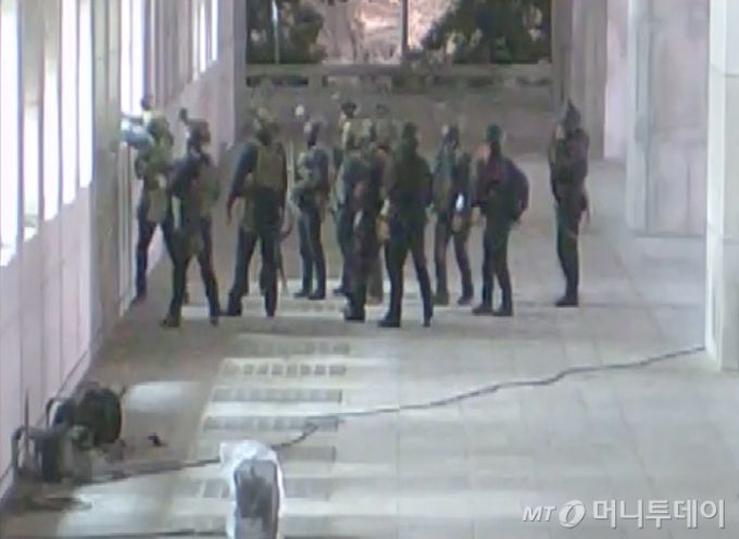 국회사무처가 계엄군의 국회 본관 진입 과정이 담긴 CCTV를 지난 4일 공개했다. 김민기 국회사무총장은 국방부가 헬기로 24차례에 걸쳐 무장한 계엄군 230여 명을 국회 경내로 진입시켰다며 0시 40분에는 계엄군 50여 명을 추가로 국회 외곽 담장을 넘어 진입시켰다고 전했다.  사진은 창문을 깨고 국회 진입 시도하는 계엄군 모습. / 사진=국회사무처