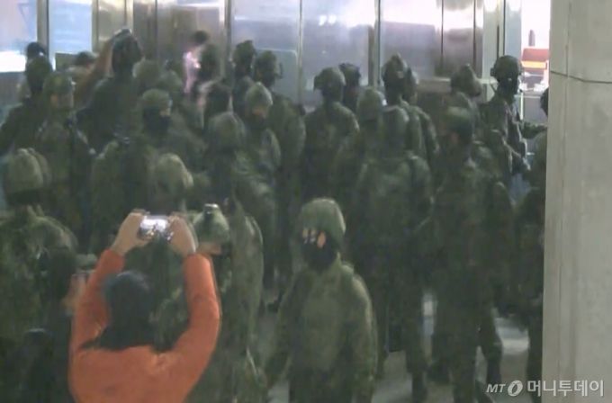 국회사무처가 계엄군의 국회 본관 진입 과정이 담긴 CCTV를 지난 4일 공개했다.   김민기 국회사무총장은 국방부가 헬기로 24차례에 걸쳐 무장한 계엄군 230여 명을 국회 경내로 진입시켰다며 0시 40분에는 계엄군 50여 명을 추가로 국회 외곽 담장을 넘어 진입시켰다고 전했다.  사진은 국회 본관 진입을 시도하는 계엄군 모습. / 사진=국회사무처