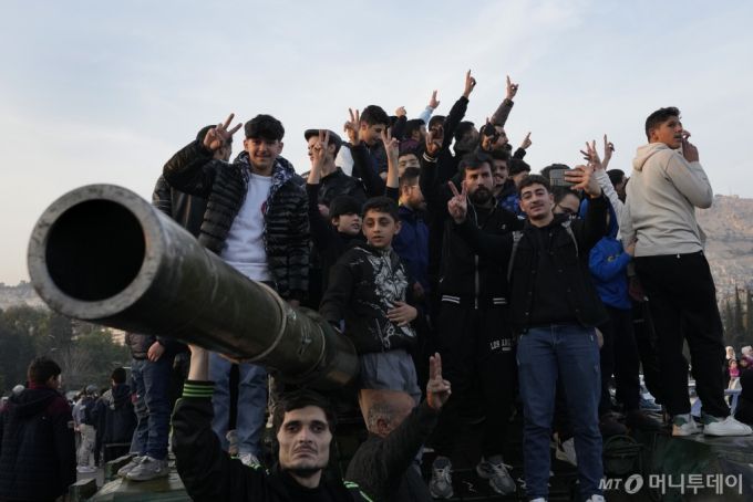 [다마스쿠스=AP/뉴시스] 9일(현지시각) 시리아 다마스쿠스에서 시민들이 거리에 버려진 시리아 정부군 전차에 올라가 바샤르 알아사드 정권의 붕괴를 축하하고 있다. 2024.12.10.