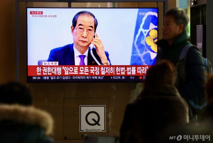 [서울=뉴시스] 김명년 기자 = 윤석열 대통령 탄핵안 가결 하루 뒤인 15일 오전 서울 용산구 서울역 대합실에서 시민들이 한덕수 권한대행 관련 뉴스를 시청하고 있다. 2024.12.15. kmn@newsis.com /사진=김명년