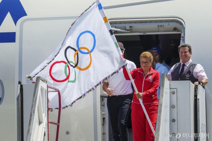 [로스앤젤레스=AP/뉴시스] 캐런 배스 미국 로스앤젤레스(LA) 시장이 12일(현지시각) 캘리포니아주 LA 국제공항에 도착해 올림픽 대회기를 들고 비행기에서 내리고 있다. LA 첫 여성 시장인 배스는 전날 프랑스 파리에서 열린 2024 파리올림픽 폐회식에서 파리 첫 여성 시장인 안 이달고로부터 오륜기를 건네받았다. 2024.08.13. /사진=민경찬