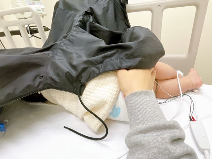 심전도 측정 기기를 몸에 달고 누워있는 아기. 응급실 조명 조절이 어려워 점퍼로 얼굴을 덮어 놓았다. /사진=최우영 기자