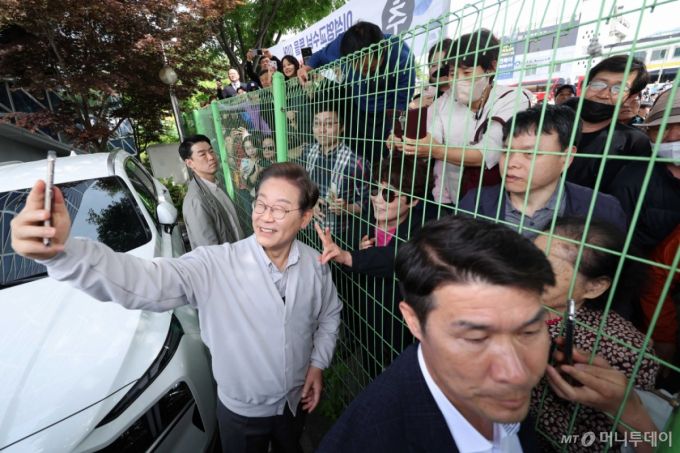 [전주=뉴시스] 민심을 청취하는 '경청 투어'에 나선 이재명 더불어민주당 대선후보가 7일 전북 전주시 완산구 풍남문 인근에서 철조망 너머에 있는 시민들과 셀카를 찍고 있다. 2025.05.07.