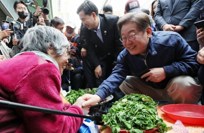 [인제=뉴시스] 조성우 기자 = 민심을 청취하는 '경청 투어'에 나선 이재명 더불어민주당 대선후보가 2일 오후 강원도 인제군 원통전통시장에서 나물을 파는 어르신과 대화하고 있다. 2025.05.02. xconfind@newsis.com /사진=조성우