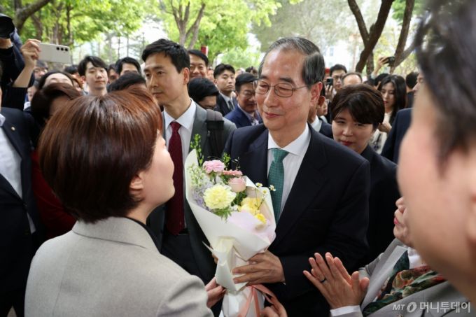 [서울=뉴시스] 조성우 기자 = 한덕수 무소속 대선 후보가 8일 김문수 국민의힘 대선 후보와의 단일화 관련 회동을 하기 위해 서울 여의도 국회 강변서재에 도착, 꽃다발을 받고 있다. 2025.05.08.  xconfind@newsis.com /사진=조성우