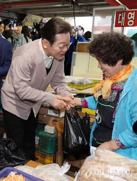 [영천=뉴시스]  민심을 청취하는 '경청 투어'에 나선 이재명 더불어민주당 대선후보가 9일 경북 영천시 영천공설시장에서 말린 고추를 구매한 뒤 상인을 격려하고 있다. 2025.05.09.