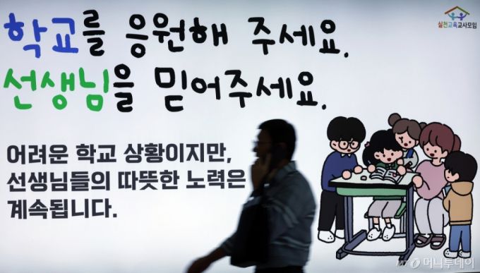 서이초 교사 순직 1주기(18일)를 앞둔 지난해 7월 16일 서울 중구 봉래동 지하철 서울역에 실천교육교사모임이 모금을 통해 게시한 추모 광고 앞으로 시민이 지나고 있다/사진=뉴스1 /사진=(서울=뉴스1) 박정호 기자