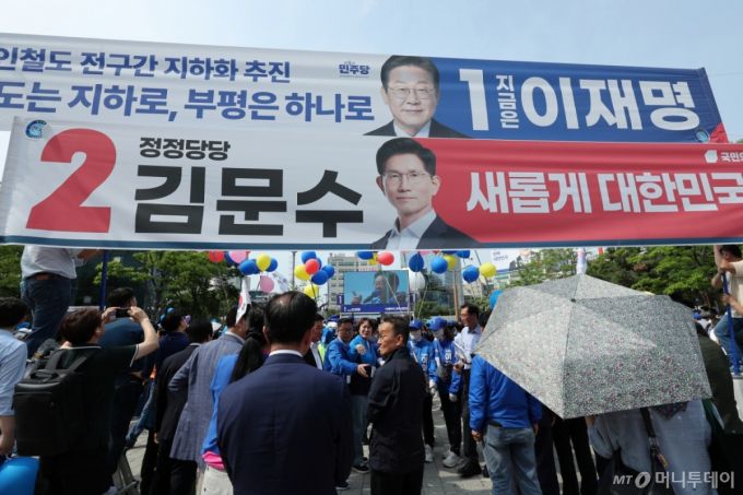 (인천=뉴스1) 안은나 기자 = 이재명 더불어민주당 대통령 후보가 사흘째 수도권 표심잡기에 나선 21일 오후 인천 부평역 광장을 찾아 지지를 호소하는 가운데 이 후보와 김문수 국민의힘 후보 현수막이 걸려 있다. 2025.5.21/뉴스1  Copyright (C) 뉴스1. All rights reserved. 무단 전재 및 재배포,  AI학습 이용 금지. /사진=(인천=뉴스1) 안은나 기자