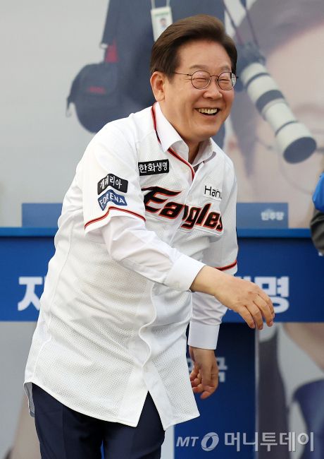 [대전=뉴시스] 이재명 더불어민주당 대선후보가 31일 오후 대전 서구 대전시청 앞 보라매공원에서 열린 유세에서 송진우 전 한화이글수 투수가 전달한 유니폼을 입고 투구 동작을 하고 있다. 2025.05.31.