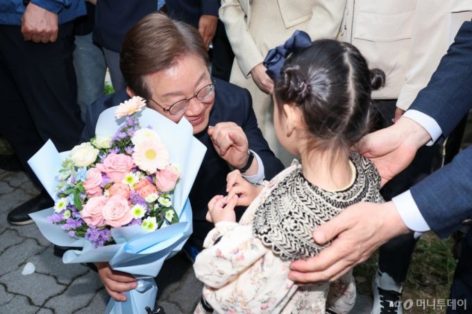 (진천=뉴스1) 안은나 기자 = 이재명 더불어민주당 대통령 후보가 2차 골목골목 경청투어에 나선 5일 오후 충북 진천군의 혁신도시 상가를 찾아 한 어린이로부터 꽃다발을 선물받은 뒤 약속을 하고 있다. 2025.5.5/뉴스1  Copyright (C) 뉴스1. All rights reserved. 무단 전재 및 재배포,  AI학습 이용 금지. /사진=(진천=뉴스1) 안은나 기자