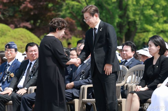 [서울=뉴시스] 고범준 기자 = 이재명 대통령이 6일 서울 동작구 국립서울현충원에서 열린 제70회 현충일 추념식에서 유해 발굴로 다시 아버지(고 송영환 일병)를 만난 송재숙 씨와 악수하고 있다. 2025.06.06. bjko@newsis.com /사진=고범준