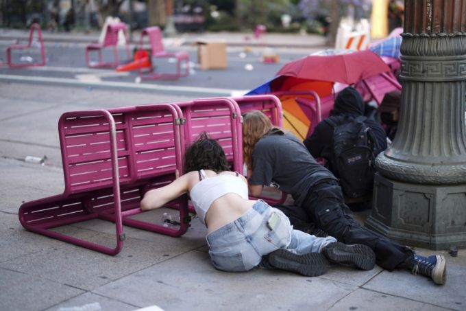 [로스앤젤레스=AP/뉴시스] 8일(현지 시간) 미 캘리포니아주 로스앤젤레스 도심 메트로폴리탄 구치소 인근 101번 고속도로에서 이민세관단속국(ICE)의 불법 이민자 단속 및 체포에 항의하는 시위대가 의자 뒤로 몸을 숨기고 있다. 2025.06.09.