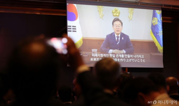 16일 서울 중구 롯데호텔에서 열린 한일 국교정상화 60주년 기념 리셉션에서 이재명 대통령의 축사 영상이 나오고 있다. / 사진=뉴스1