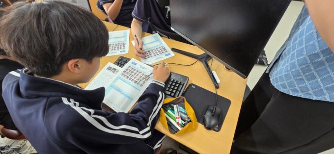 방송통신위원회와 한국지능정보사회진흥원(NIA) 주관으로 진행된 광남중 디지털 윤리 교육에서 학생들이 제시된 교육자료 속 사진을 보며 '행복한 표정'과 '행복하지 않은 표정'을 구분하기 위해 토론하고 있는 모습 / 사진=황국상 기자