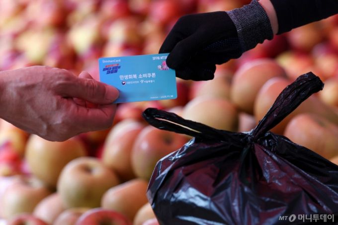 23일 서울 시내의 한 전통시장에서 한 시민이 민생회복 소비쿠폰을 이용해 과일을 구매하고 있다./사진=뉴시스