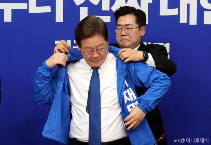 [서울=뉴시스] 조성봉 기자 = 박찬대 더불어민주당 대표 직무대행 겸 원내대표가 28일 오전 서울 여의도 국회에서 열린 최고위원회의에서 이재명 더불어민주당 제21대 대통령 선거 후보의 선거운동복을 입혀주고 있다. 2025.04.28. suncho21@newsis.com /사진=조성봉