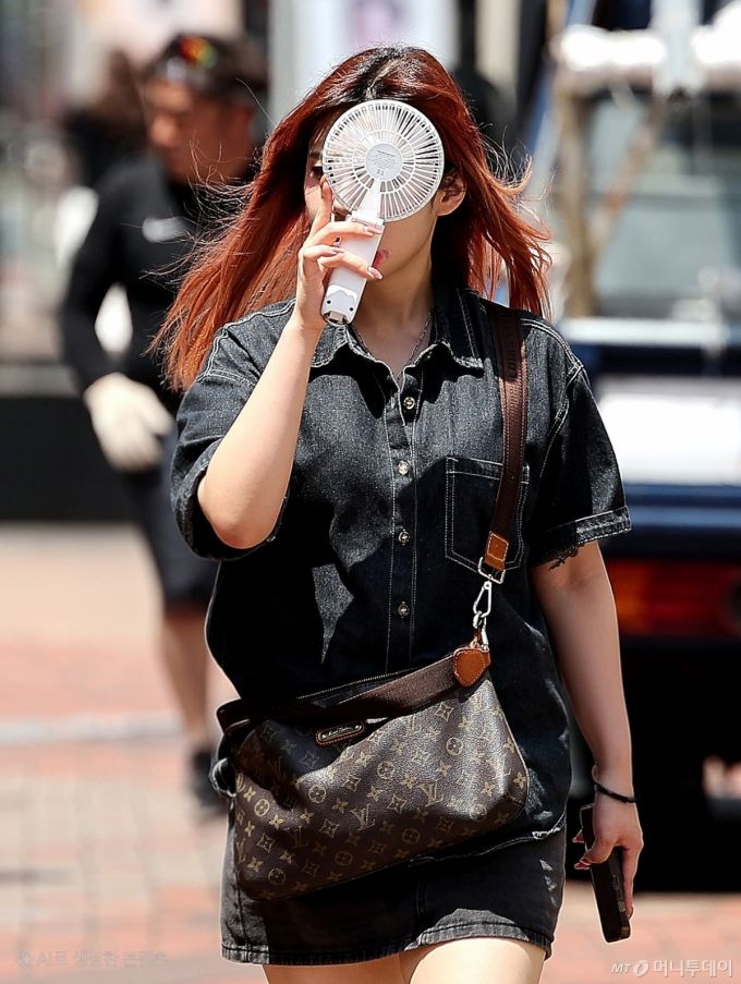 [대구=뉴시스] 이무열 기자 = 폭염이 연일 계속된 23일 대구 중구 동성로에서 한 시민이 손 선풍기를 들고 길을 걷고 있다. 2025.07.23. lmy@newsis.com /사진=이무열