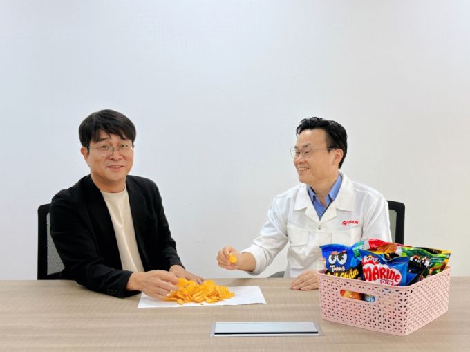 (왼쪽부터) 오리온 베트남 법인의 정종연 마케팅 팀장 상무, 문영복 오리온 베트남법인 연구소장이 오리온 스낵을 맛보는 모습./사진제공=오리온