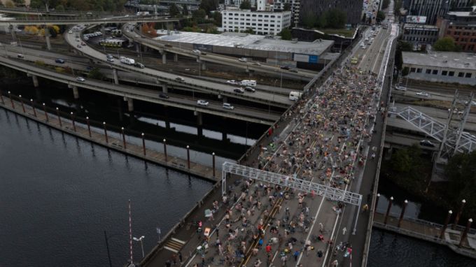 12일(현지시간) 미 오리건주 포틀랜드 번사이드 브리지에서 '나체 자전거 시위'(Naked Bike Ride) 참가자들이 도널드 트럼프 대통령의 주 방위군 투입 시도에 항의하며 도로에 누워 시위하고 있다. /AP=뉴시스