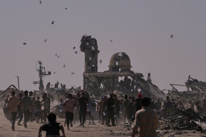 팔레스타인 주민들이 20일(현지 시간) 가자지구 남부 칸유니스에서 이스라엘 드론이 투하한 ‘옐로 라인(이스라엘의 가자지구 내 철수선) 접근 금지 경고' 전단을 받고 있다. /AP=뉴시스