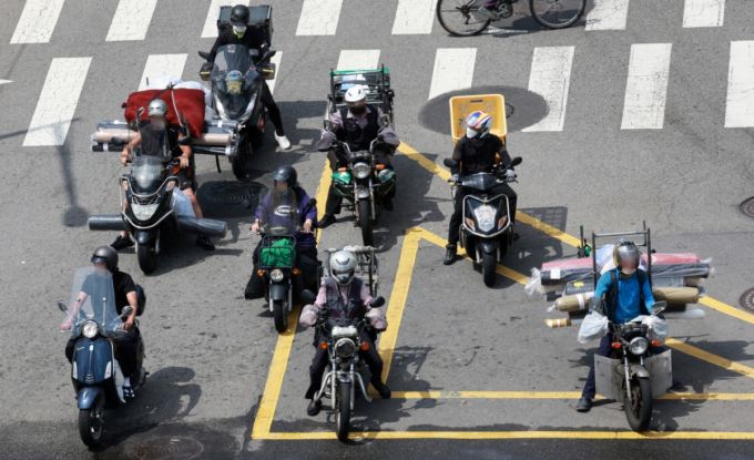 찜통 더위가 이어지고 있는 지난 7월23일 오후 서울 종로구의 한 도로에서 배달업 종사자들이 달궈진 아스팔트 위에서 신호를 기다리고 있다. /사진=뉴시스