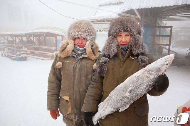 15일(현지시간) 러시아 야쿠츠크에서 생선을 파는 상인 마리나 크리볼루츠카야와 마리안나 우가이가 딱딱하게 언 생선을 든 채 사진을 찍고 있다. 이들 가게엔 냉동 창고가 따로 없다. /사진=뉴스1