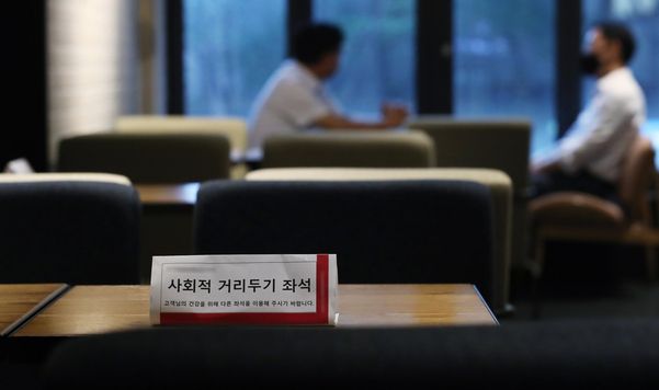 사회적 거리두기 2단계가 조치 중인 21일 서울의 한 카페에서 마스크를 착용한 이용객과 착용하지 않은 이용객이 대화를 하고 있다./ 연합뉴스