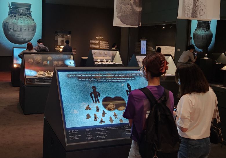 8일 서울 용산구 국립중앙박물관에서 관람객이 투명 OLED가 설치된 진열대에서 토기 뚜껑에 달린 토우(흙 인형) 설명을 보고 있다. /최지희 기자