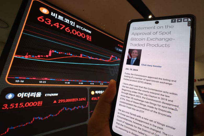 미국 증권거래위원회(SEC)가 비트코인 현물 상장지수펀드(ETF)의 상장을 승인한 11일 오전 서울 서초구 빗썸 고객센터에 비트코인을 비롯한 가상화폐 시세 현황이 표시되고 있다. 휴대 전화 화면은 SEC 공식 사이트 내 관련 게시글. /연합뉴스