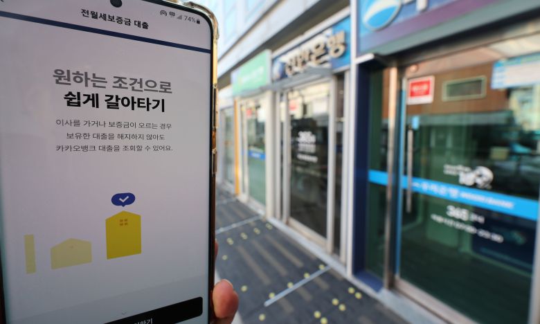 휴대전화 뱅킹앱과 서울 시내 거리의 은행 현금자동입출금기(ATM). /연합뉴스