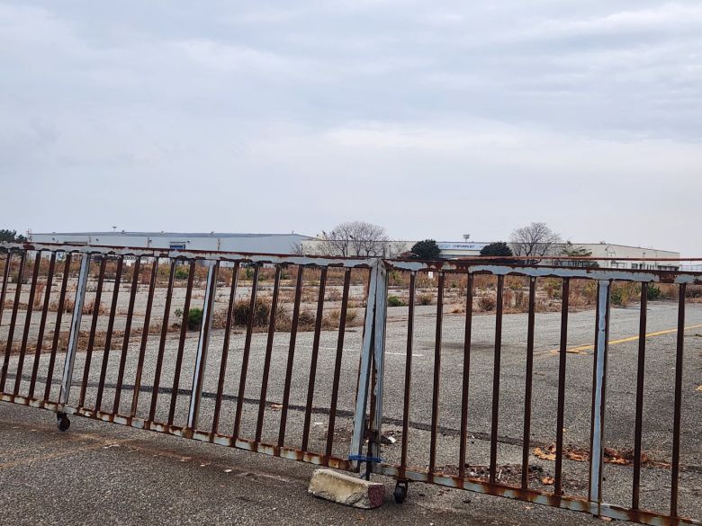 옛 한국GM 군산공장의 출고 대기장. 굳게 닫힌 녹슨 철문 뒤로 잡초가 무성한 빈 땅과 멀리 빛바랜 쉐보레 로고가 보인다. GM은 지난 2018년 군산공장 가동을 중단했고 이듬해 매각했다. /진상훈 기자