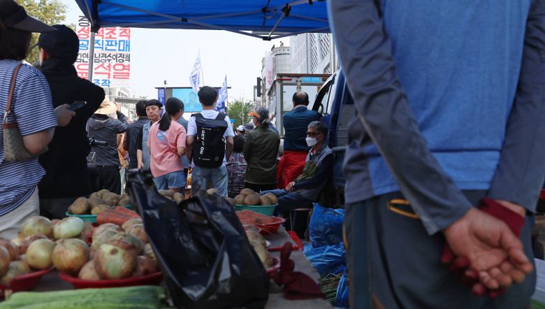 지난달 25일 충남 당진시 당진전통시장에서 한 채소가게 상인이 더불어민주당 이재명 대선 후보의 유세를 지켜보고 있다. /연합뉴스