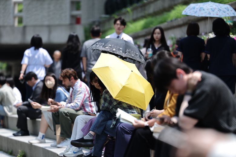 5월 26일 오후 서울 청계광장에서 겉옷을 벗거나 양산을 쓴 시민들이 올해 마지막 봄을 즐기고 있다./ 뉴스1