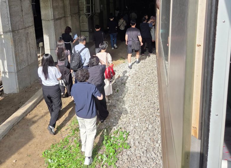 13일 오전 경의중앙선 신촌역 인근에서 사다리차 전도사고가 발생해 가좌역~신촌역 구간이 양방향 통제된 가운데 서울역행 경의중앙선 열차에 탑승한 승객들이 열차에서 내려 선로를 따라 대피하고 있다. /뉴스1