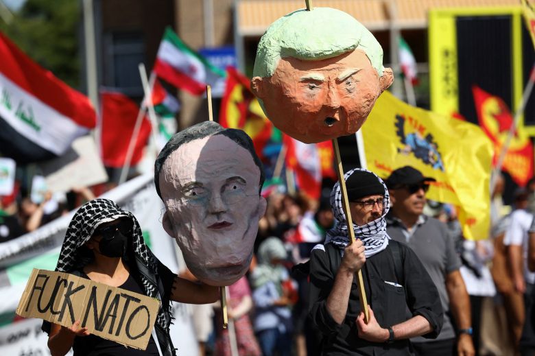 시위대가 22일 네덜란드 헤이그에서 열리는 NATO 정상회담에 반대하는 시위를 벌이면서 NATO 사무총장 마크 뤼터와 미국 대통령 도널드 트럼프 모습이 담긴 종이인형 두상을 들고 있다. /연합뉴스