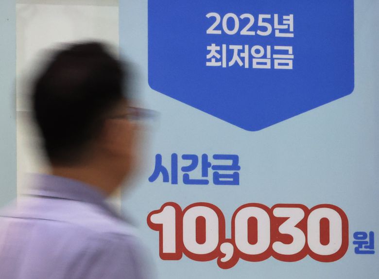 서울 마포구 서부고용복지플러스센터에서 시민이 최저임금 홍보물 앞을 지나고 있다./연합뉴스