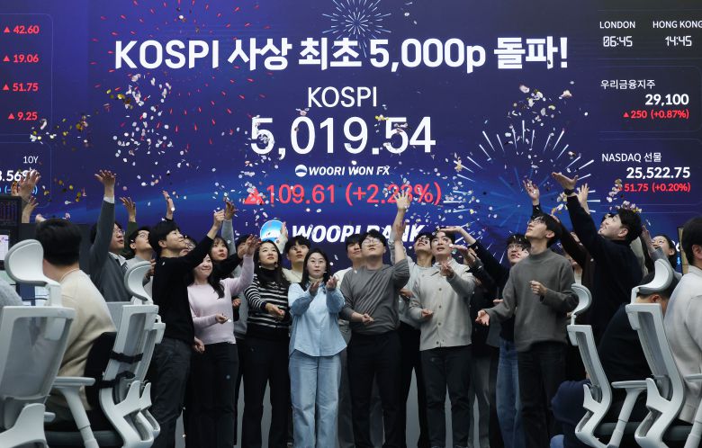 한국 증시가 사상 처음으로 '코스피 5000' 쾌거를 달성한 22일 서울 중구 우리은행 본점 딜링룸에서 직원들이 장중 최고가가 찍힌 전광판을 배경으로 코스피 5000 돌파를 축하하고 있다. 이날 코스피는 이재명 대통령이 '코스피 5000' 공약을 내걸고 임기를 시작한 지 7개월 만에 꿈의 5000을 돌파하며 한국 자본시장의 역사를 새로 썼다. /뉴스1