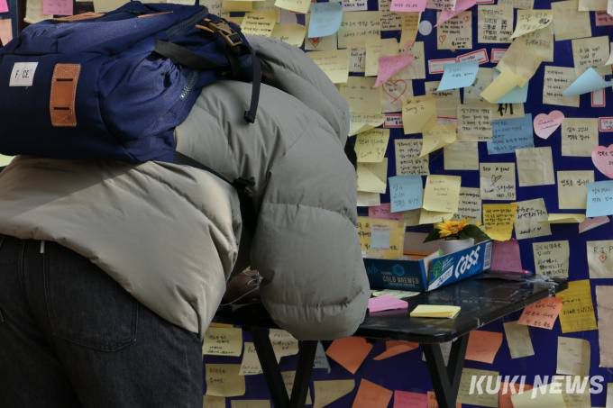 추모의벽을 방문한 한 시민이 포스트잇에 글을 적고 있다.   사진=안세진 기자