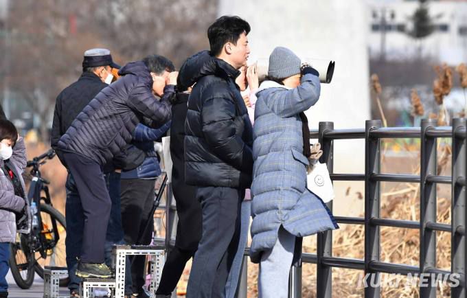 중랑천철새보호구역의 탐조대에서 시민들이 물 한가운데 모여있는 겨울철새 및 텃새들을 관찰하고 있다.